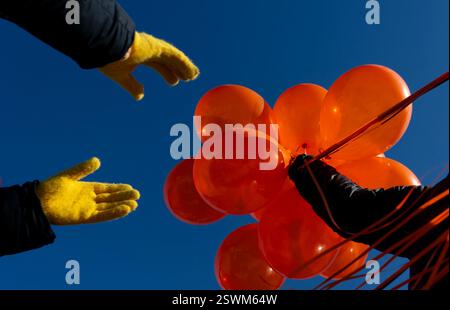 Washington, Usa. Februar 2025. Freiwillige halten orangene Ballons an einem leeren Shabbat-Tisch in der National Mall zu Ehren von Kfir und Ariel Bibas, den jüngsten Geiseln, die nach dem Terroranschlag am 7. Oktober 2023 in Israel am Freitag, den 21. Februar 2025 in Washington, DC, entführt und getötet wurden. Die Leichen der Kleinkinder Ariel und Kfir Bibas wurden nach 501 Tagen der Vermutung nach Israel zurückgebracht. und ihre Fotos werden an einen Tisch für die ermordeten Opfer des Angriffs gestellt. Foto: Leigh Vogel/UPI Credit: UPI/Alamy Live News Stockfoto