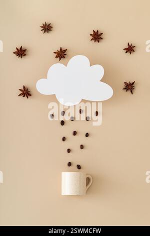 Kreatives Layout aus wolkenförmiger Papierkarte, Kaffeebohnen Regen, Sternanis und Kaffeetasse auf beigefarbenem Hintergrund. Minimales Konzept. Stockfoto