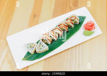 Köstliche Sushi-Brötchen, die künstlerisch auf einem eleganten Teller mit Wasabi und eingelegtem Ingwer in einem modernen Ambiente serviert werden Stockfoto