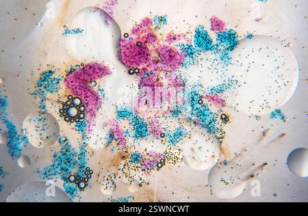 Abstrakte Zusammensetzung mit Wasser, Blasen, Öltropfen und blauen und violetten Farbflecken auf weißem Hintergrund Stockfoto