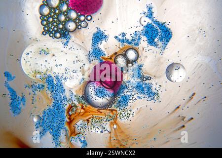 Abstrakte Zusammensetzung mit Wassertropfen, Öl und blauen, orangen und violetten Tintenflecken auf weißem Hintergrund Stockfoto