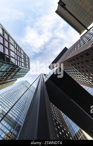 Schauen Sie morgens mitten in der Skyline nach oben. Turmblöcke und moderne Glasfronten bei Sonnenaufgang. Schöner Überblick über die Wolkenkratzer und deren Surro Stockfoto