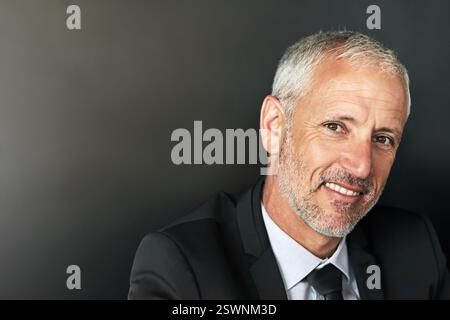 Porträt, Angestellter und reifer Mann im Studio, Lächeln und Firmenprofi auf grauem Hintergrund. Gesicht, Person und Model mit Glück, Mockup-Raum Stockfoto