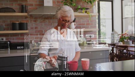 Bild der Datenverarbeitung über eine ranghohe afroamerikanische Frau, die Kaffee in der Küche zubereitete Stockfoto