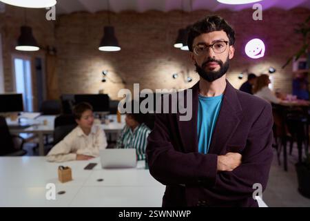 Selbstbewusster Geschäftsmann posiert mit gekreuzten Armen in einem modernen Büro Stockfoto