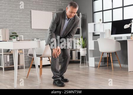 Reifer Geschäftsmann mit Knieschmerzen in der Praxis Stockfoto