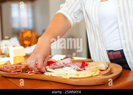 Nahaufnahme einer Person, die Artikel aus einer Gourmet-Wurst- und Käseplatte auswählt. Stockfoto