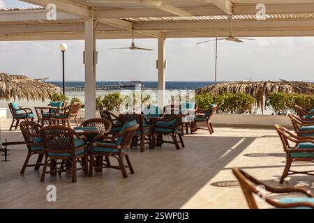Korbstühle und Tische unter einem Baldachin schaffen eine entspannte Atmosphäre in einem Strandbar-Restaurant mit Blick auf das rote Meer Stockfoto