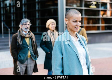 Erfolgreiche Geschäftsfrau im mittleren Erwachsenenalter, die draußen mit Geschäftskollegen steht. Stockfoto