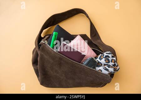 Flach liegend mit Reiseutensilien in Wildledertasche auf pastellfarbenem Hintergrund. Stockfoto