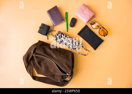 Flache Grundausstattung mit Wildledertasche auf pastellfarbenem Hintergrund. Stockfoto