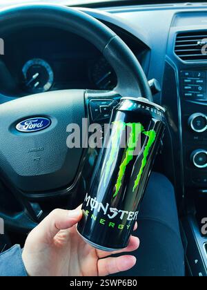 Kiew, Ukraine - 16. Februar 2025: Hand hält Monster Energy Drink im Auto, wobei der Schwerpunkt auf den Innenraum des Fahrzeugs gelegt wird. Stockfoto