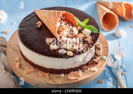 Leckerer Kekskuchen mit Schokoladenglasur und Sahne. Kekskuchen mit Streuseln, Eiskegel und Glasur. Stockfoto