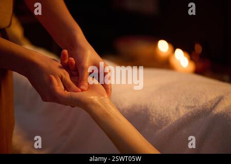 Mittlere Nahaufnahme von nicht erkennbaren weiblichen Händen mit ätherischem Öl zur Tiefenmassage Stockfoto