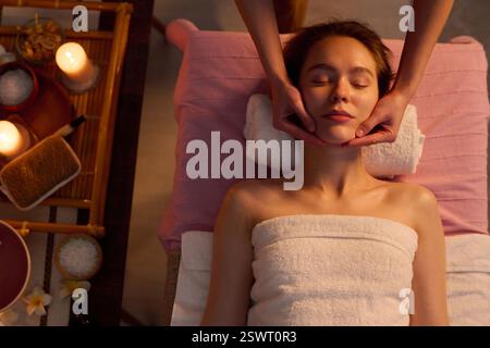 Top-Down einer jungen erwachsenen Frau mit geschlossenen Augen, die eine Anti-Aging-Massage für das Gesicht bekommt Stockfoto