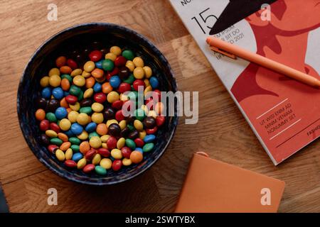 Flache Schüssel aus Keramik gefüllt mit runden, beschichteten Süßigkeiten in verschiedenen Farben auf dem Couchtisch im Wohnzimmer, Kopierraum Stockfoto