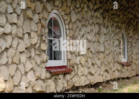Die Steinmauer mit zwei Bogenfenstern im antiken Stil. Stockfoto
