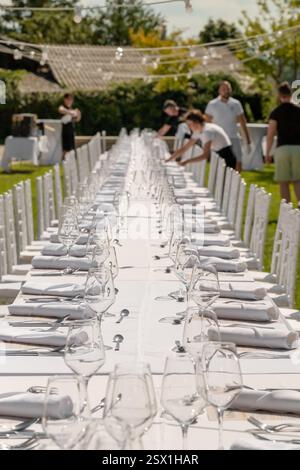 Hochzeitstisch mit Tellern, weißen Stühlen, Servietten und Weingläsern Stockfoto