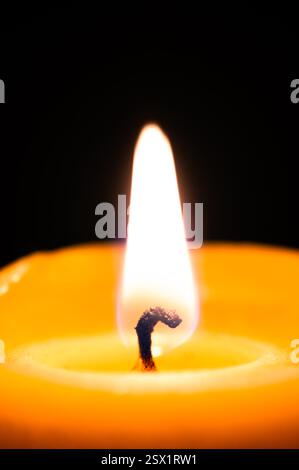Nahaufnahme der Flamme auf Bienenwachskerze vor schwarzem Hintergrund Stockfoto