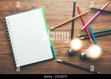 Notizbuch mit Idee und vielen bunten Bleistiften auf Holztisch Stockfoto
