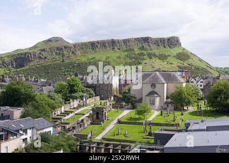 Canongate Kirk und Friedhof mit Salisbury Crags und Arthurs sitzen im Hintergrund. Edinburgh, Großbritannien. Stockfoto