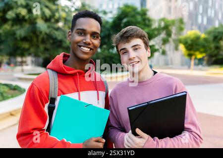 Zwei junge männliche Studenten lächeln zusammen vor der Kamera auf dem Campus Stockfoto