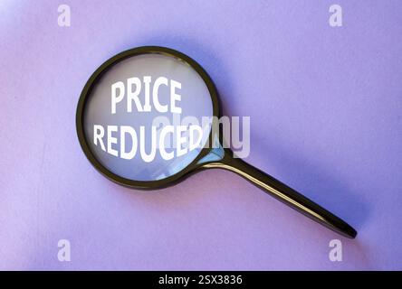 Symbol für reduzierte Preise. Lupe mit Konzeptwort Preis reduziert. Schöner lila Hintergrund. Business- und preisreduziertes Konzept. Kopierbereich Stockfoto