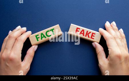 Fakt oder Fälschungssymbol. Konzeptwort Fakt oder Fälschung auf Holzblöcken. Geschäftsmann Hand. Wunderschöner tiefblauer Hintergrund. Business and Fact oder Fake Concept. Stockfoto