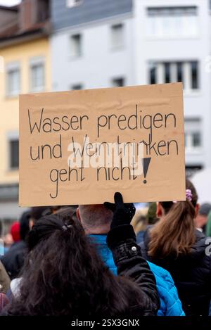 Einsiedeln, Schweiz. Februar 2025. Ein Demonstrant hält ein Schild bei der Demonstration „Gegen den Rechtsruck“ in Einsiedeln. Auf dem Plakat steht: „Man kann kein Wasser predigen und Wein trinken.“ Der Protest lehnt den Aufstieg der rechten Politik und die Anwesenheit der AfD-Ko-Leiterin Alice Weidel in der Stadt ab. Quelle: Fabienne Koch/Alamy Live News Stockfoto