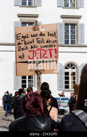 Einsiedeln, Schweiz. Februar 2025. Ein Demonstrant hält ein Schild bei der Demonstration „Gegen den Rechtsruck“ in Einsiedeln. Auf dem Plakat steht: „Egal, was du tust, du bist Teil dieser Zeit. Nie wieder ist es JETZT!“ Der Protest lehnt den Aufstieg der rechten Politik und die Anwesenheit der AfD-Ko-Leiterin Alice Weidel in der Stadt ab. Quelle: Fabienne Koch/Alamy Live News Stockfoto