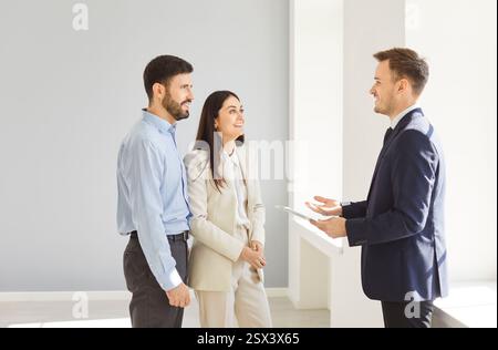Mann und Frau reden mit Mann Makler in einem neuen Haus und bereit, Hausbesitzer zu werden. Stockfoto