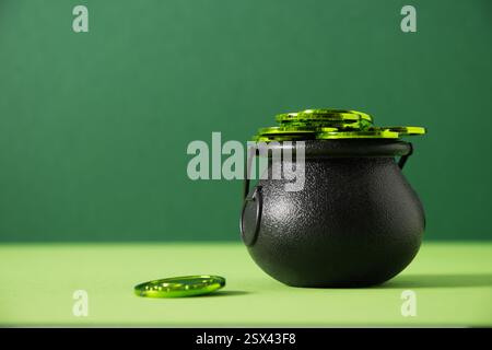 St. Patrick's Day Black Pot, Schatz des Leprechaun, Pot voller grüner Münzen auf festlichem grünem Hintergrund. Nahaufnahme. Grußkarte. Stockfoto