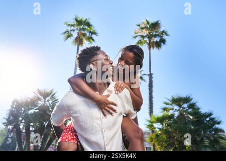 Der Freund gibt seiner Freundin während des Sommerurlaubs auf einem Strandland Huckepack. Stockfoto