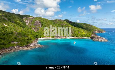 Die markante felsige Küste ist von dichtem Grün umgeben und trifft auf das kristallklare türkisfarbene Wasser des Ozeans. Seychellen, Mahe. Stockfoto