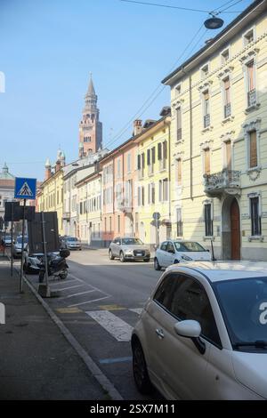 Cremona, Italien 9. Februar 2025 Beige Fiat 500 parkte auf einer Straße von Cremona mit Torrazzo-Glockenturm, der über bunten Gebäuden ragt Stockfoto