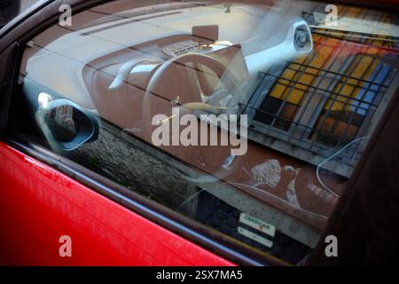 Cremona, Italien, 9. Februar 2025 Armaturenbrett eines roten Citroen C1, sichtbar durch das Fenster, die Reflexionen einer benachbarten Gebäudefassade in einem urb einfangen Stockfoto