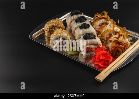 Auf einer wunderschön angeordneten Sushi-Platte werden verschiedene Brötchen mit Fischrogen, Sesam und knusprigen Zutaten serviert. Begleitet von Wasabi und eingelegt Stockfoto