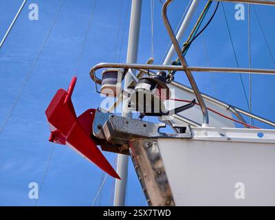 Ein hellroter Anker ist sicher an der Seite eines Segelbootes befestigt Stockfoto