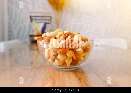 Cashews, Erdnüsse und Mandeln auf einem Teller. Nüsse auf dem Tisch in den hellen Sonnenstrahlen. Stockfoto