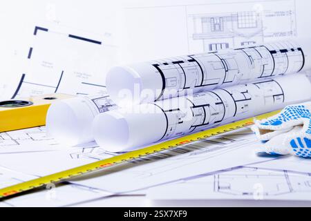 Baumeister-Werkzeuge für den Plan des Hauses. Ich bereite den Bau eines Hauses vor. Baumeister-Handschuhe und Blaupausen. Stockfoto