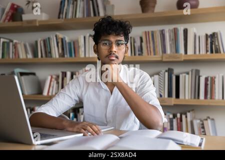 Porträt eines Studenten, der in der Universitätsbibliothek vor der Kamera posiert Stockfoto
