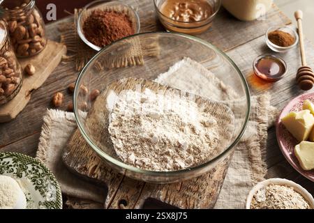 Molkenproteinpulver, gemahlene Haferflocken, Nussbutter, roher Kakao und Ahornsirup - Zutaten für hausgemachte Eiweißschokoladentafeln auf einem Tisch Stockfoto