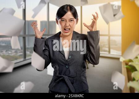 Geschäftsfrauen fühlen sich gestresst, wenn sie am Arbeitsplatz mit der Papierkram herumfliegen. Konzept von Geschäftsproblem und Überlastung Stockfoto