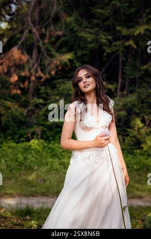 Atemberaubende Braut posiert anmutig in einem Frühlingspark, inmitten blühender Bäume. Strahlt Eleganz aus, Stockfoto