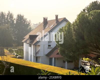 Charmantes weißes Haus eingebettet zwischen üppigem Grün an einem sonnigen Morgen Stockfoto