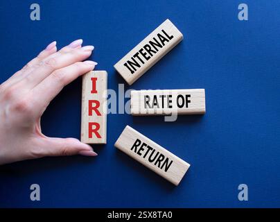 IRR - Internal Rate of Return symbol. Concept word IRR on wooden cubes. Businessman hand. Beautiful deep blue background. Business and IRR concept. Co Stockfoto