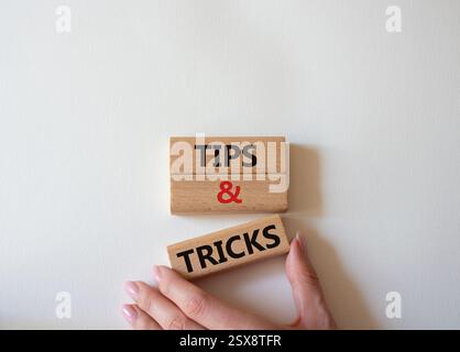 Symbol für Tipps und Tricks. Holzblöcke mit Worten Tipps und Tricks. Schöner weißer Hintergrund. Geschäftsmann Hand. Geschäftskonzept und Tipps und Tricks. Stockfoto