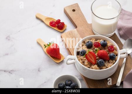 Buchweizenflocken mit Erdbeeren und Heidelbeeren in keramischer weißer Platte auf Holztablett mit Kopierraum Stockfoto