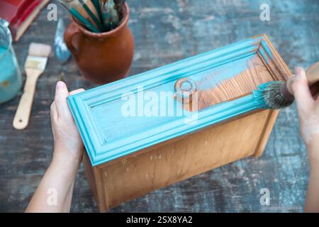 Holzmöbel mit Kreidemalerei aus menschlicher Hand. Alte Holzmöbel werden mit brandneuer, farbenfroher Kreidefarbe erneuert. Stockfoto