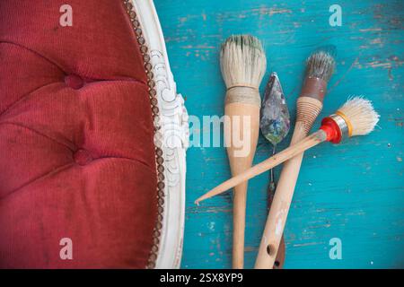 Bürsten und Möbel auf dem Arbeitstisch. Alte Holzmöbel werden mit brandneuer, farbenfroher Kreidefarbe erneuert. Stockfoto